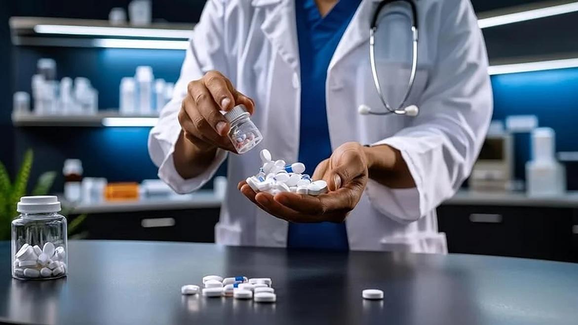 A pharmacist in a white coat counting capsules into their hand at a dispensing bench