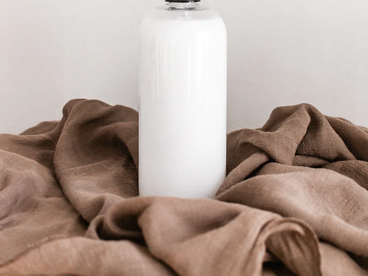 A white bottle standing in folds of brown linen
