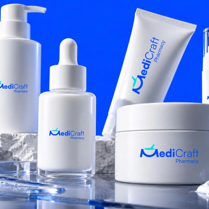White pump bottles, a dropper bottle, a tube and a jar of cream on a stone plinth against a blue ground